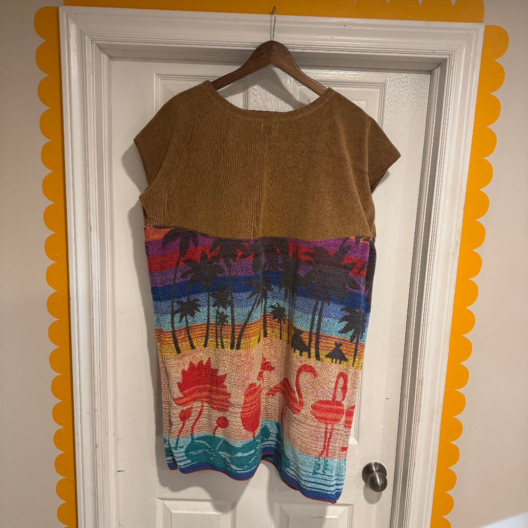 Brown dress with colorful flamingo design on a hanger against a white door.
