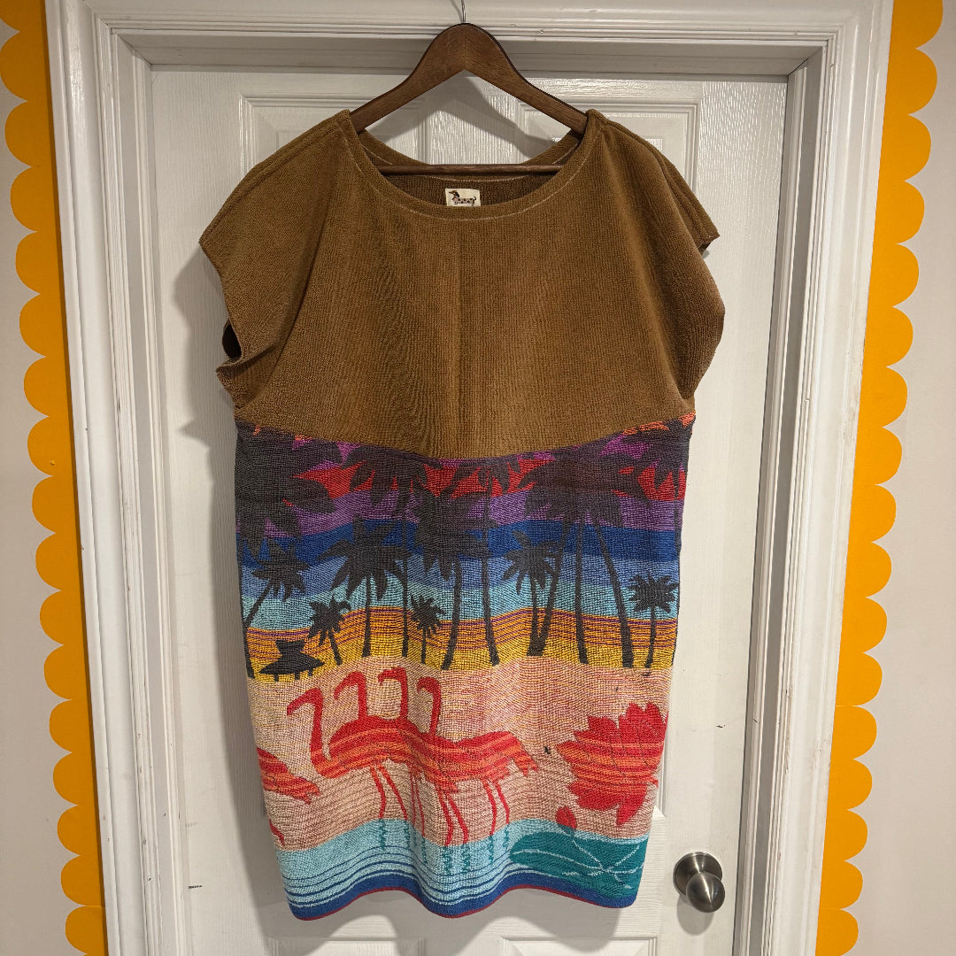Brown sleeveless top with colorful flamingo design on a hanger against a white door.