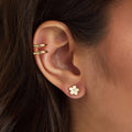 Close-up of an ear wearing gold earrings with a blurred background