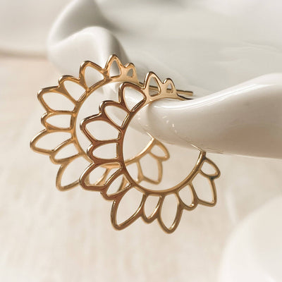 Gold floral earring on a white ceramic stand