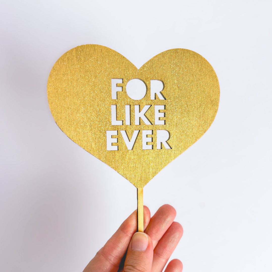 Gold heart-shaped sign with 'FOR LIKE EVER' text on a white background