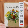 Plantable card with flowers and a house illustration, held by a person.