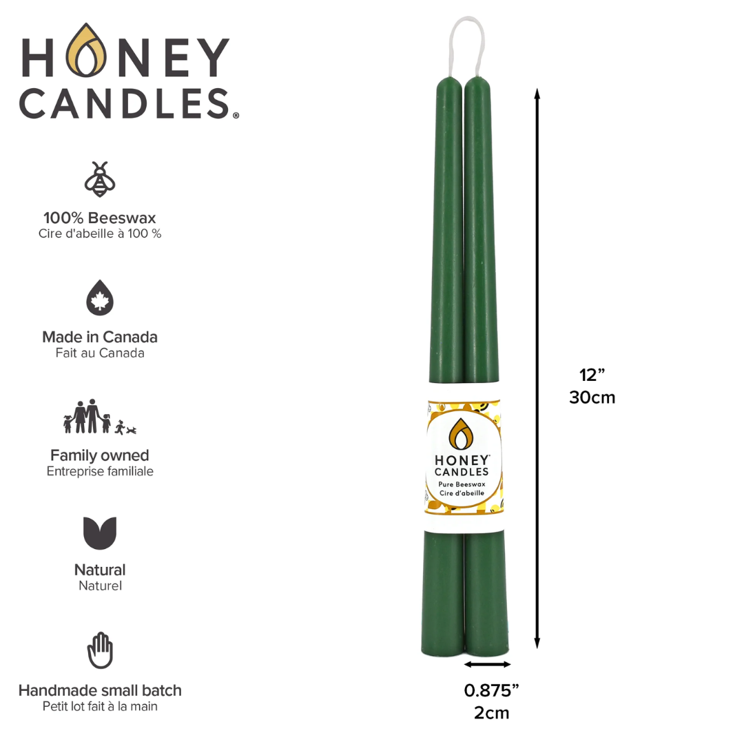 Two green beeswax candles standing upright, tied together with a string. The candles have a label that says "HONEY CANDLES 100% Pure Beeswax." The label also includes information about the candles, such as the fact that they are made in Canada, family-owned, and handmade in small batches.
