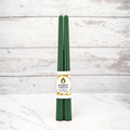Two green beeswax candles standing upright, tied together with a string. The candles have a label that says "HONEY CANDLES Pure Beeswax."