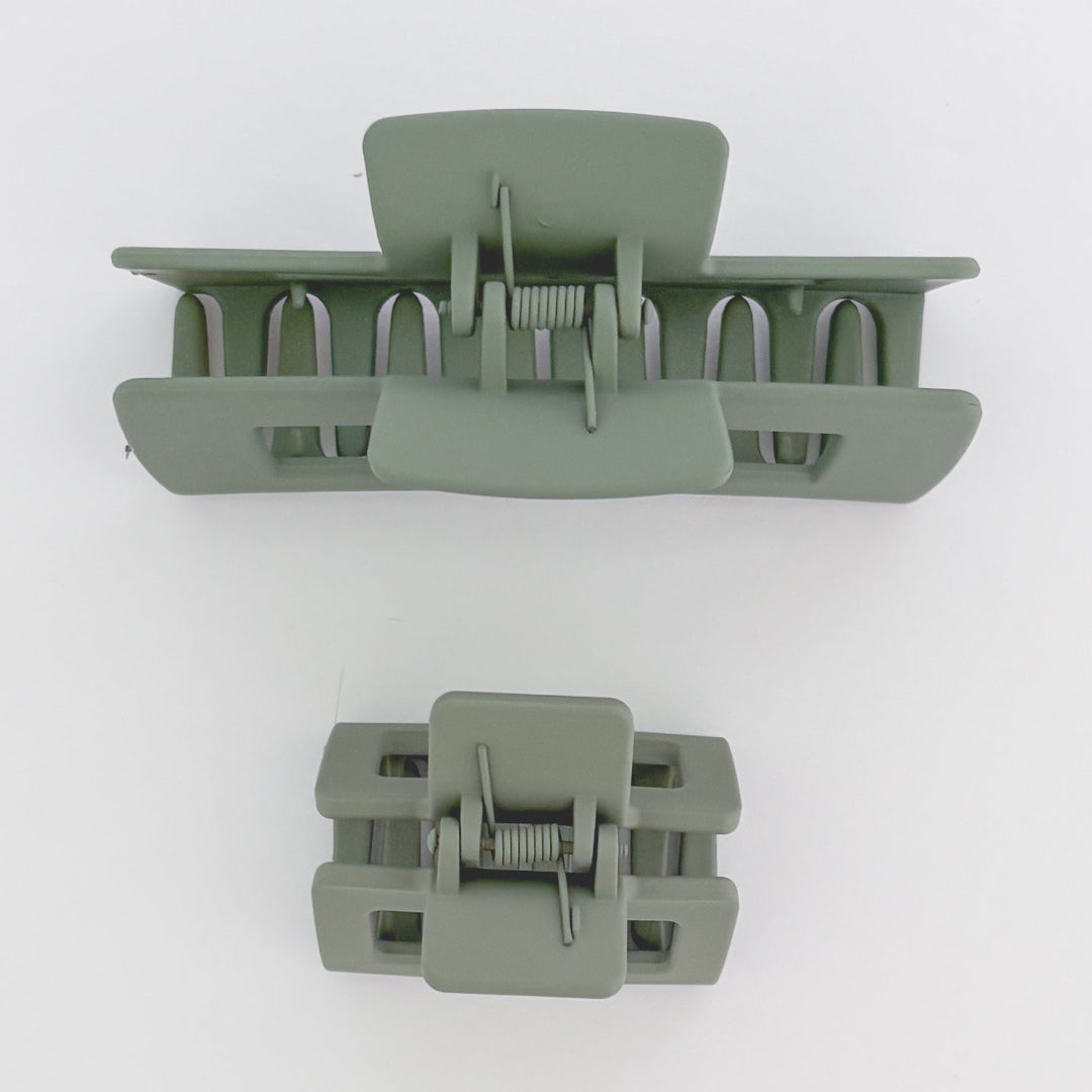 Two green hair clamps on a white background