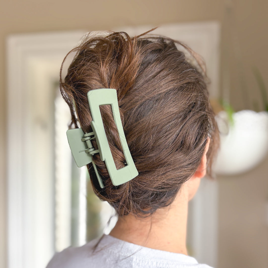 Person with a green hair clip in their brown hair against a neutral background
