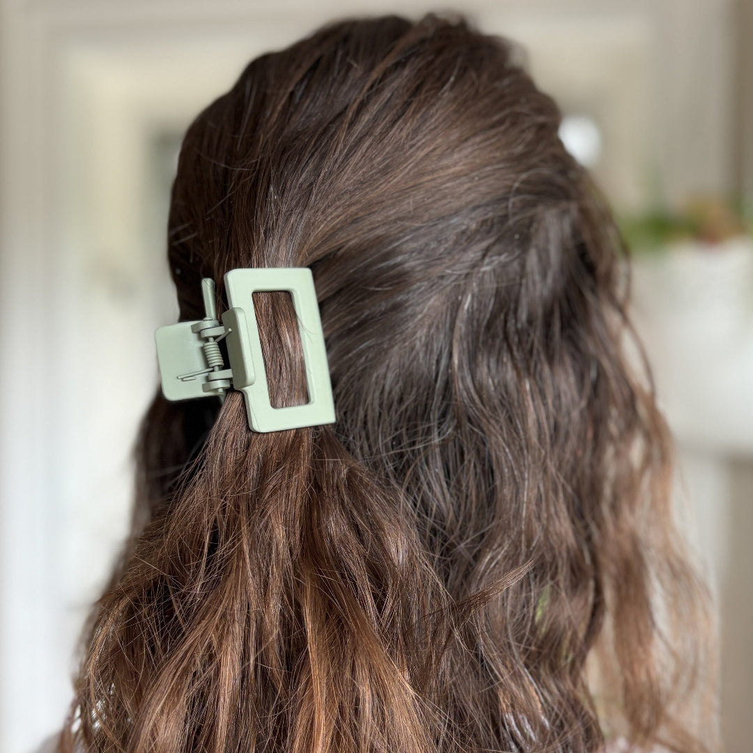 Close-up of a person's hair with a green hair clip, blurred background