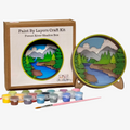 Paint by Layers Craft Kit with a completed forest river shadow box and paint supplies on a white background.
