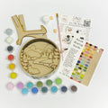 Artistic craft kit with paint, brushes, and a wooden plaque on a white background