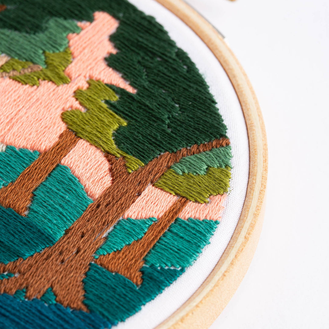 Embroidery hoop with a nature-themed design on a white background