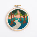 Embroidery hoop with a scenic landscape design on a white background