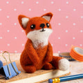 Handmade fox plush toy on a wooden surface with a pink polka dot background