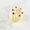 A white chocolate bath bomb decorated with a peach-colored rose and chocolate chips. The bath bomb is resting on a white marble surface.
