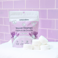 Naturebee shower steamers with packaging on a purple tiled background