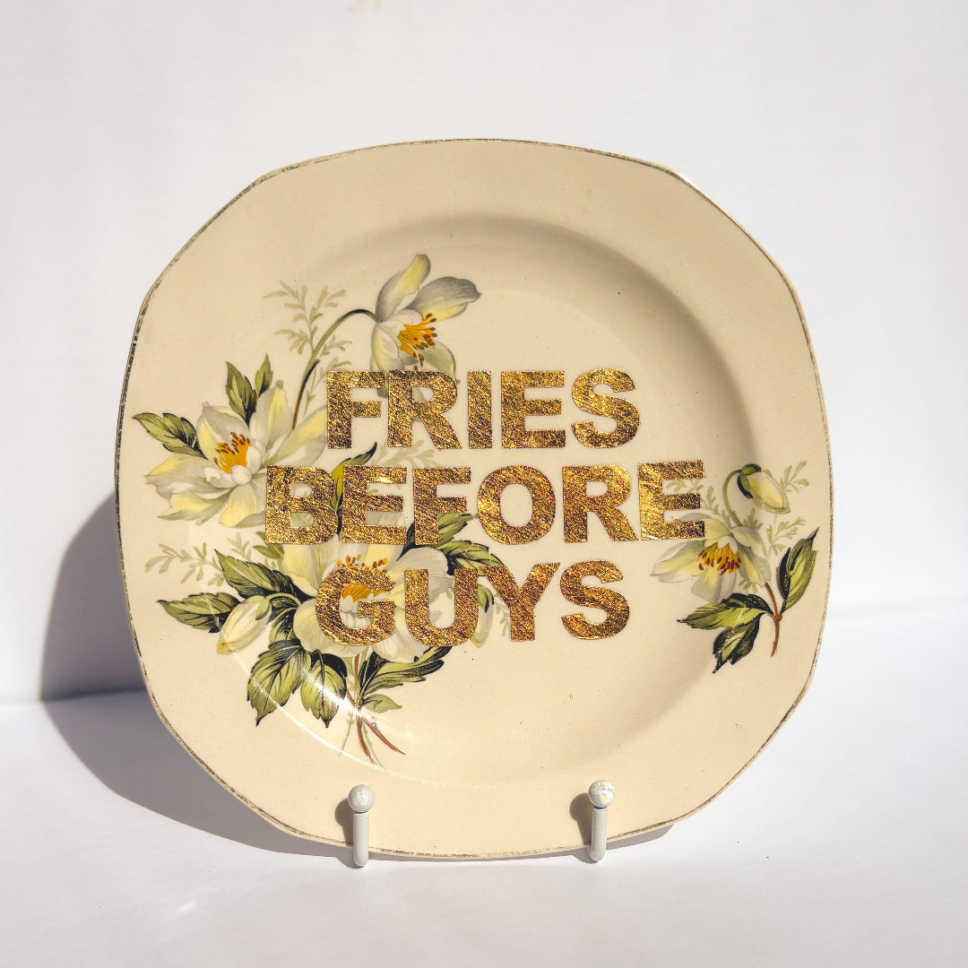 Decorative plate with floral design and 'Fries Before Guys' text on a white background