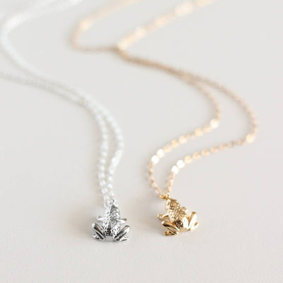 Two necklaces with frog pendants on a light background