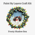 Paint by Layers Craft Kit for Frosty Shadow Box with a snowman and cabin design.