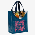 A reusable tote bag with a playful design. The bag is a dark blue color with navy handles. It features a graphic of several puppies peeking out from the top of the bag, with the text "THIS BAG MIGHT BE FULL OF PUPPIES" printed below in pink.