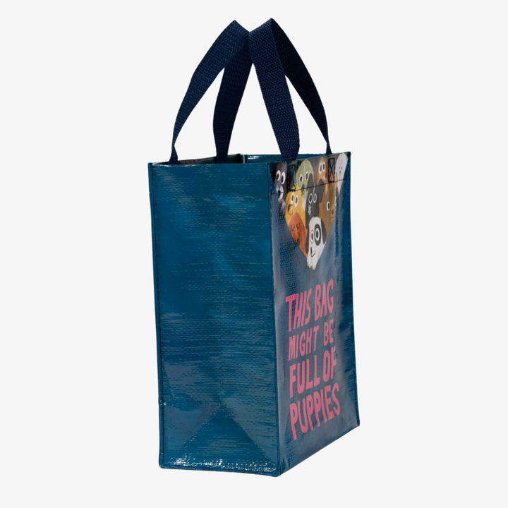 A reusable tote bag with a playful design. The bag is a dark blue color with navy handles. It features a graphic of several puppies peeking out from the top of the bag, with the text 