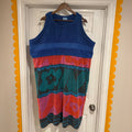 Colorful sleeveless dress with floral patterns on a hanger against a white door.