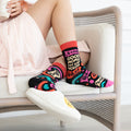 Person wearing colorful socks with text and patterns, sitting on a chair.