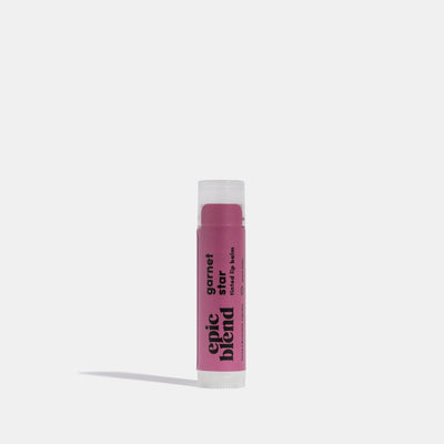 A white tube of Epic Blend Garnet Star Tinted Lip Balm with a deep pink label. The label displays the brand name, 
