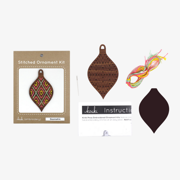 A wooden ornament shaped like a teardrop. The ornament is decorated with colorful embroidery stitches in a geometric diamond pattern.