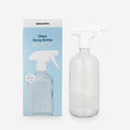 Clear glass spray bottle with white nozzle next to its packaging on a white background