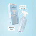 Clear glass spray bottle with packaging on a light blue background