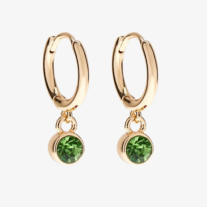 A set of three pairs of peridot earrings displayed on a green card. The set includes a pair of stud earrings, a pair of bar earrings with small peridot beads, and a pair of hoop earrings with dangling peridot stones. The card has the month 