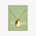 A gold necklace with a peridot stone pendant. The pendant also has the word "BEAUTY" engraved on it. The necklace is displayed on a green card with the month "August" and the brand name "Foxy Originals."