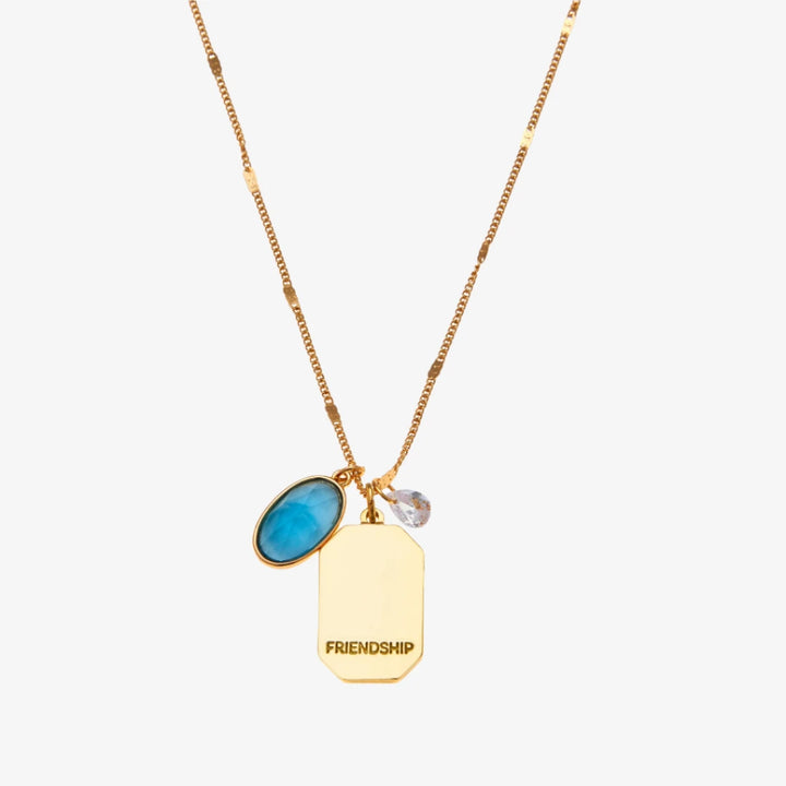 A gold necklace with a turquoise stone pendant. The pendant also has the word 