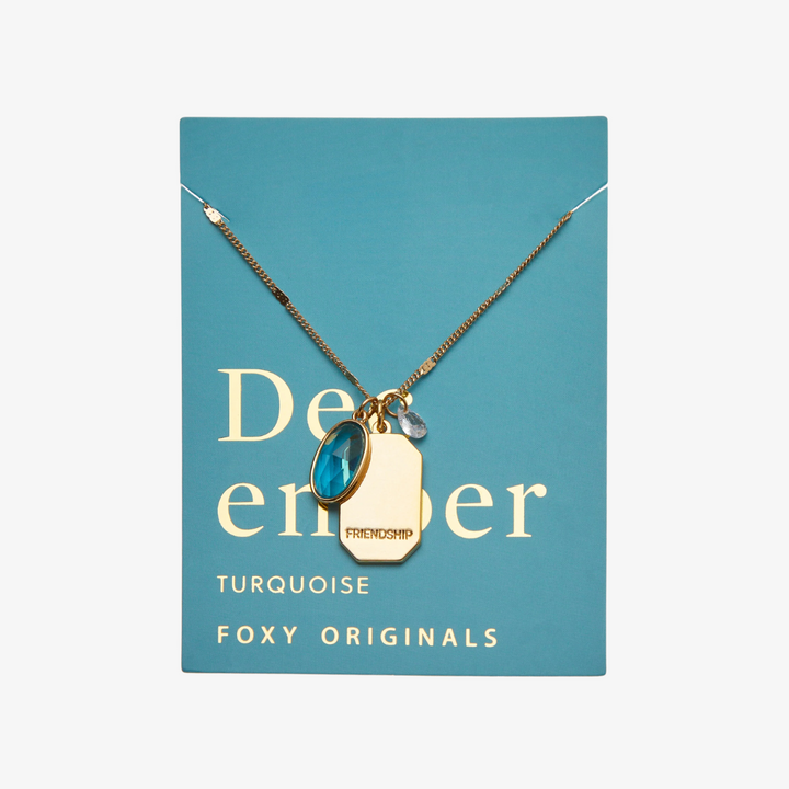 A gold necklace with a turquoise stone pendant. The pendant also has the word 