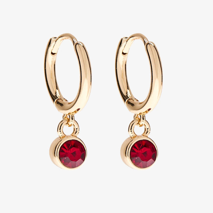 A set of three pairs of garnet earrings displayed on a red card. The set includes a pair of stud earrings, a pair of bar earrings with small garnet beads, and a pair of hoop earrings with dangling garnet stones. The card has the month 