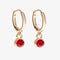 A set of three pairs of ruby earrings displayed on a red card. The set includes a pair of stud earrings, a pair of bar earrings with small ruby beads, and a pair of hoop earrings with dangling ruby stones. The card has the month 