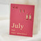 A set of three pairs of ruby earrings displayed on a red card. The set includes a pair of stud earrings, a pair of bar earrings with small ruby beads, and a pair of hoop earrings with dangling ruby stones. The card has the month 