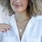 A gold necklace with a pearl stone pendant. The pendant also has the word 