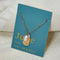 A gold necklace with a pearl stone pendant. The pendant also has the word 