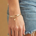 A gold layered bracelet with a small padlock charm. The bracelet has two chains of different widths, and the padlock charm hangs from the thinner chain.
