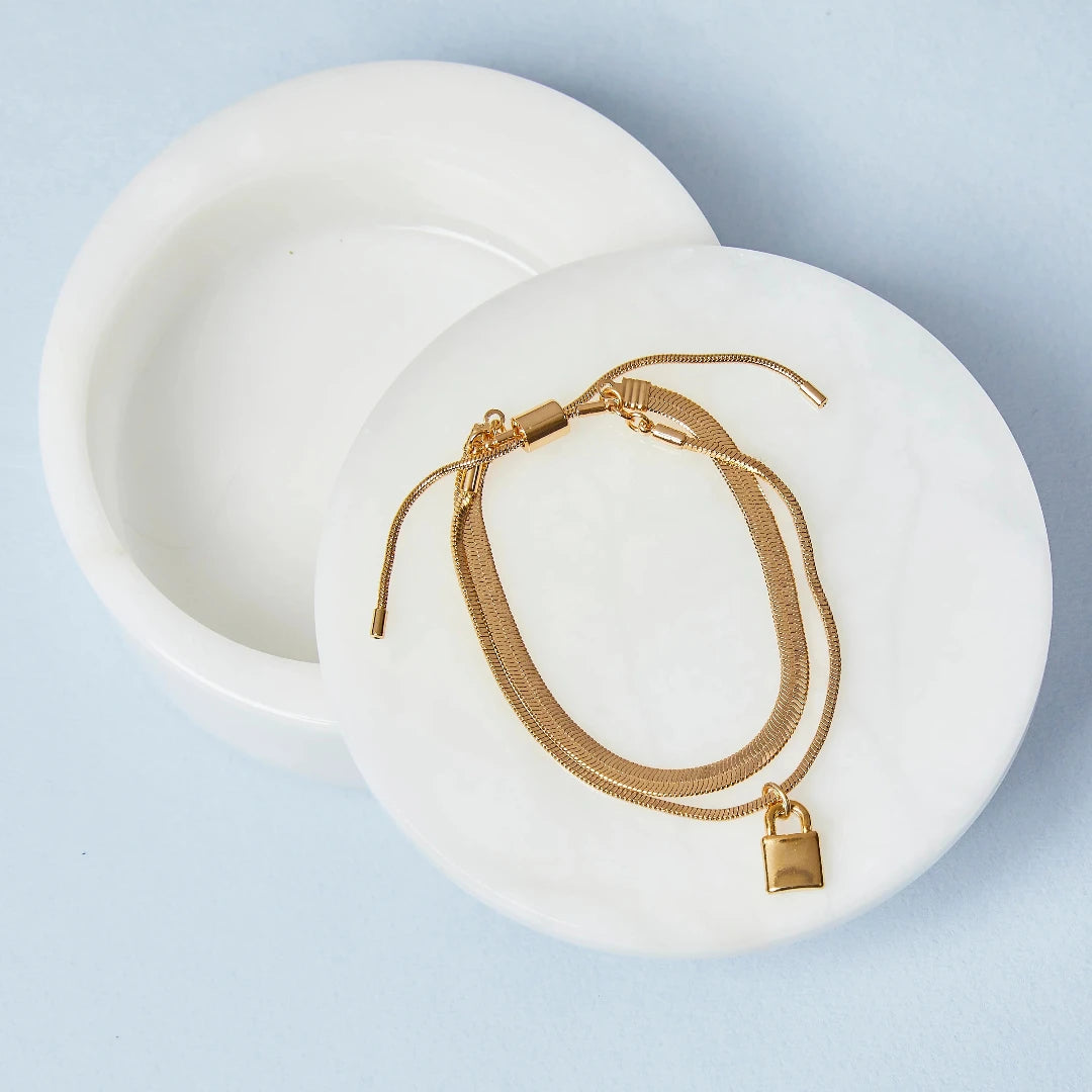 A gold layered bracelet with a small padlock charm. The bracelet has two chains of different widths, and the padlock charm hangs from the thinner chain.