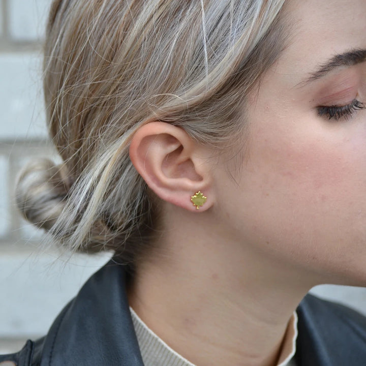 A pair of gold maple leaf stud earrings.