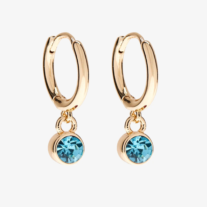 A set of three pairs of aquamarine earrings displayed on a light blue card. The set includes a pair of stud earrings, a pair of bar earrings with small aquamarine beads, and a pair of hoop earrings with dangling aquamarine stones. The card has the month 