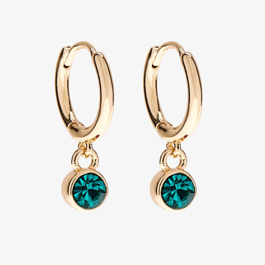 A set of three pairs of emerald earrings displayed on a green card. The set includes a pair of stud earrings, a pair of bar earrings with small emerald beads, and a pair of hoop earrings with dangling emerald stones. The card has the month "May" and the brand name "Foxy Originals."