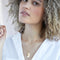 A gold necklace with a citrine stone pendant. The pendant also has the word 