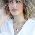 A gold necklace with a sapphire stone pendant. The pendant also has the word "TRUTH" engraved on it. The necklace is displayed on a blue card with the month "September" and the brand name "Foxy Originals."