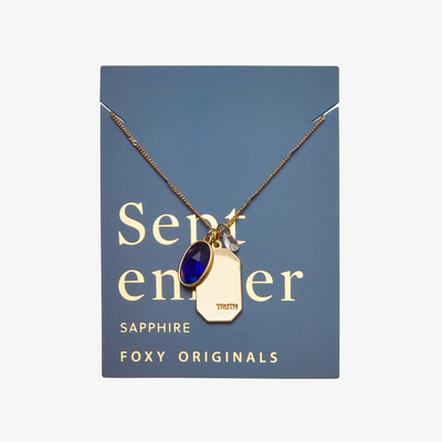 A gold necklace with a sapphire stone pendant. The pendant also has the word 