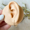 A pair of Agaveh Girl Gold Aspyn Hoops, featuring a minimalist, open curved design, displayed on a branded card with the text 'agaveh girl,' against a textured background. The earrings are dainty and modern, available in Ottawa, Ontario, Canada.