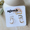 A pair of Agaveh Girl Gold Aspyn Hoops, featuring a minimalist, open curved design, displayed on a branded card with the text 'agaveh girl,' against a textured background. The earrings are dainty and modern, available in Ottawa, Ontario, Canada.