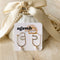 A pair of gold hoop earrings with a single pearl dangling from each hoop. 