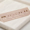 A set of gold stud earrings representing the days of the week. The earrings are arranged on a pink card with the words 